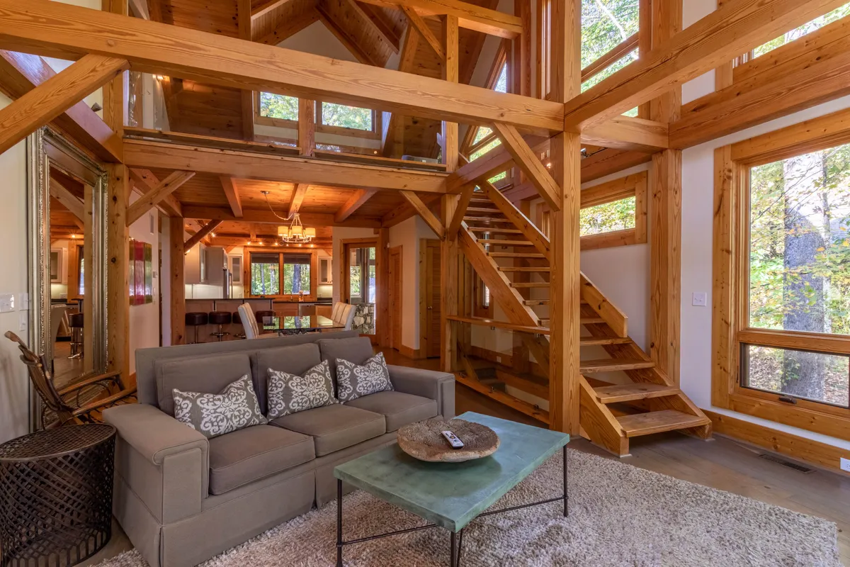 A comfortable living space with a sofa and coffee table set near expansive windows. The room is filled with natural light and provides a warm, welcoming setting for relaxing, socializing, or holding informal gatherings.