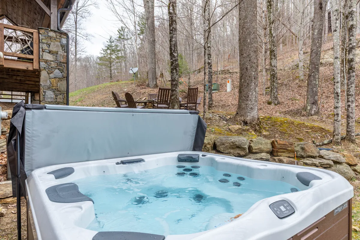 A hot tub on a wooden deck, surrounded by trees and lounge chairs, offering a tranquil spot to relax and socialize while being immersed in nature. The sunset sky hints at evening gatherings and relaxation after a day of adventure.