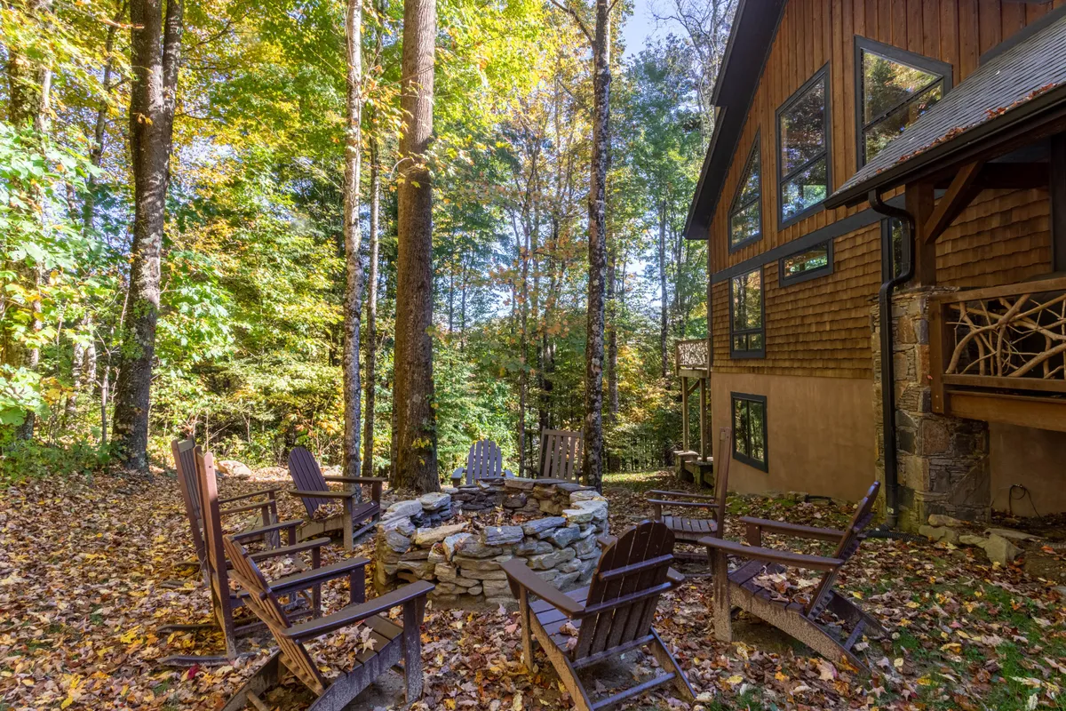 An inviting exterior scene featuring a cozy fire pit surrounded by trees and the deck of a townhome. Guests are gathered around the fire, sharing stories, enjoying drinks, and creating lasting memories beneath the night sky.